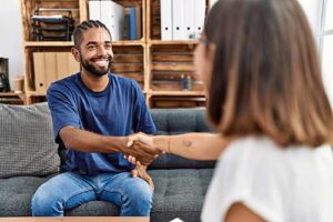 an adult man shakes hand with an adult woman meeting for the first time in motivational interviewing
