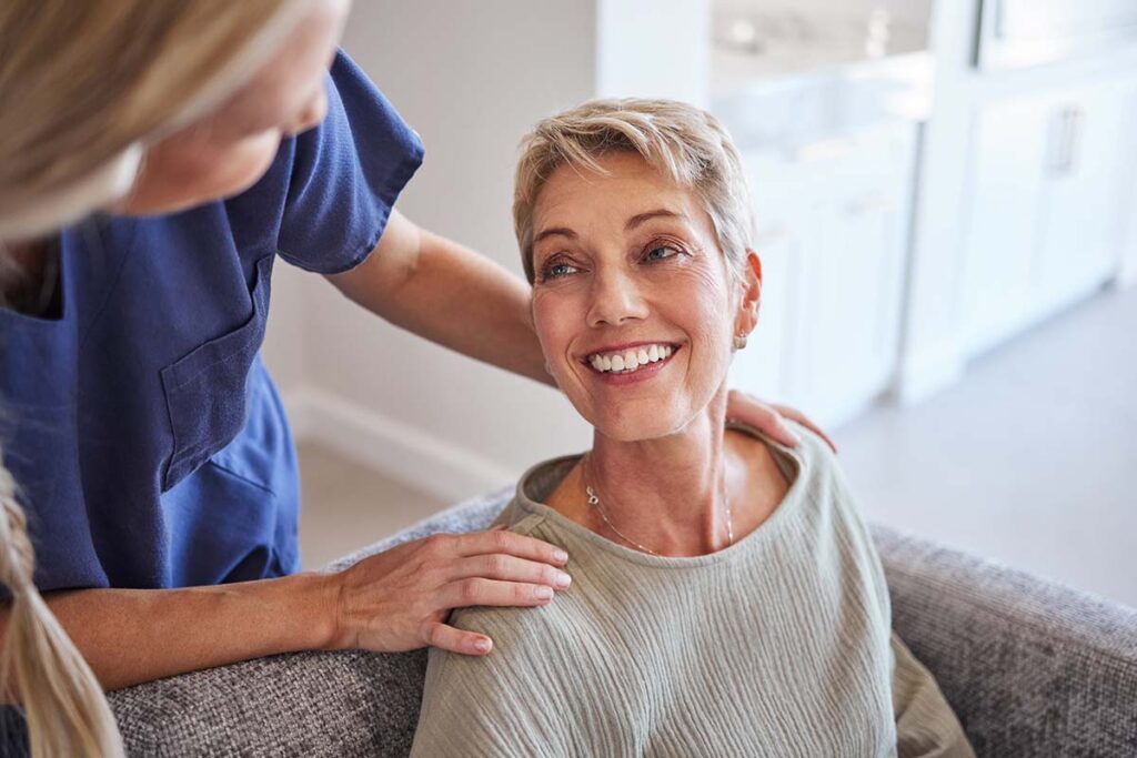 woman sits in a chair looking up and smiling at her nurse while enduring the benefits of suboxone treatment
